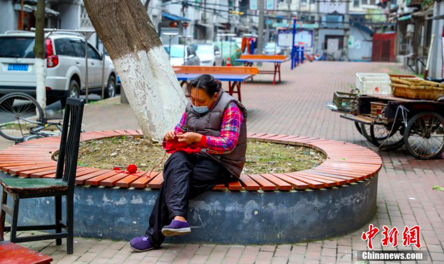 Một người dân bên trong khu thôn mới Trường Hàng của Vũ Hán đang ngồi đan một chiếc áo len - Ảnh: Chinanews