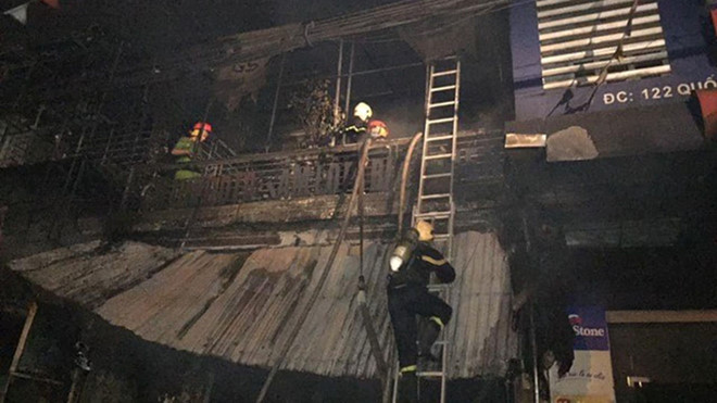 Lực lượng cứu hỏa mang theo bình dưỡng khí để tiếp cận bên trong cửa hàng kinh doanh thiết bị ô tô - Ảnh: Tân Kỳ