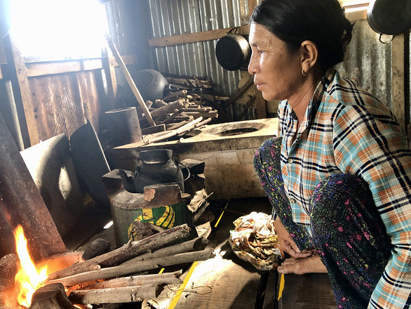 Bà Lời nhóm lửa chuẩn bị nấu cơm trên bè - Ảnh: DIỆU QUÍ