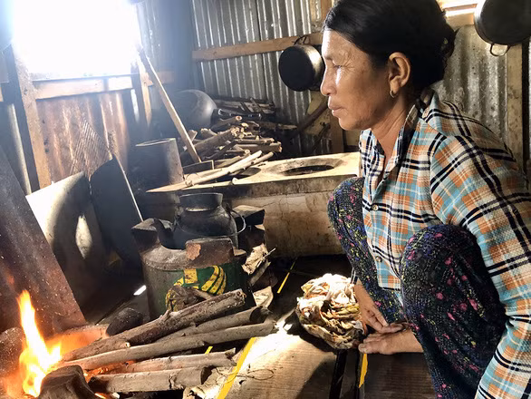 Bà Lời nhóm lửa chuẩn bị nấu cơm trên bè - Ảnh: DIỆU QUÍ