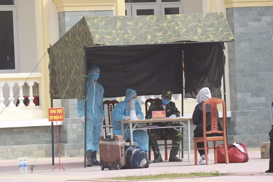 Nhân viên y tế làm thủ tục tiếp đón người từ vùng dịch về cách ly tại Trường Quân sự - Bộ Tư lệnh Thủ đô Hà Nội. Ảnh T.Vương