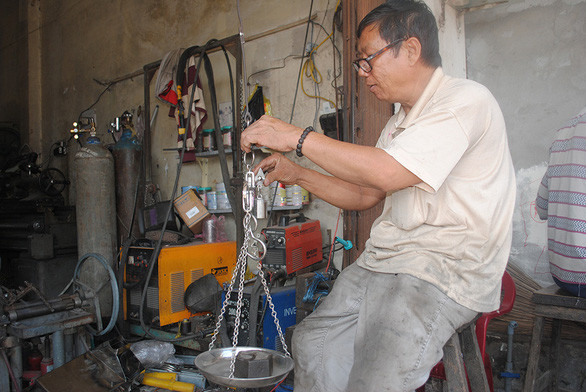 Ông Nguyễn Minh Dũng bên chiếc cân treo do mình sản xuất - Ảnh: T.NHƠN