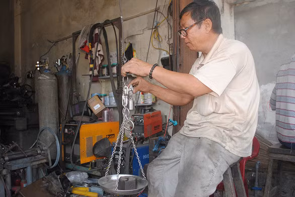 Ông Nguyễn Minh Dũng bên chiếc cân treo do mình sản xuất - Ảnh: T.NHƠN