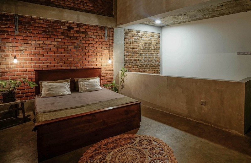 Phòng ngủ trên tầng 2 làm bằng gạch thô gợi lên sự mộc mạc, gần gũi.
