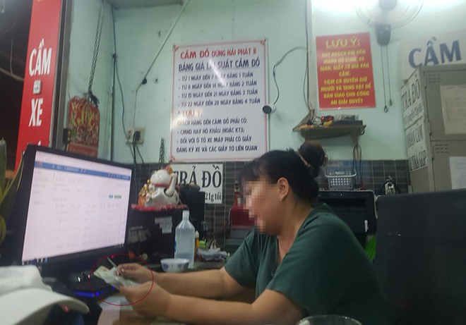 Người phụ nữ trong tiệm cầm đồ đang lựa CMND cũ bán cho khách ẢNH: TRÁC RIN