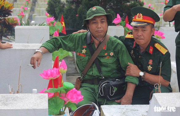 Những người lính Vị Xuyên năm xưa lặng người trước phần mộ đồng đội. Ảnh: HIÊN HUYỀN