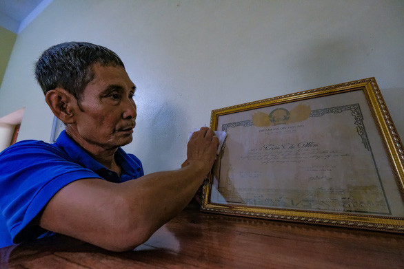 Ông Vũ Đức Dậu, em trai liệt sĩ Trần Thị Mai (đại đội 915, đội 91 Bắc Thái), bên tấm bằng Tổ quốc ghi công trên bàn thờ. Ngày ấy chị Mai hi sinh khi chưa kịp chụp được tấm ảnh. Ảnh: NAM TRẦN