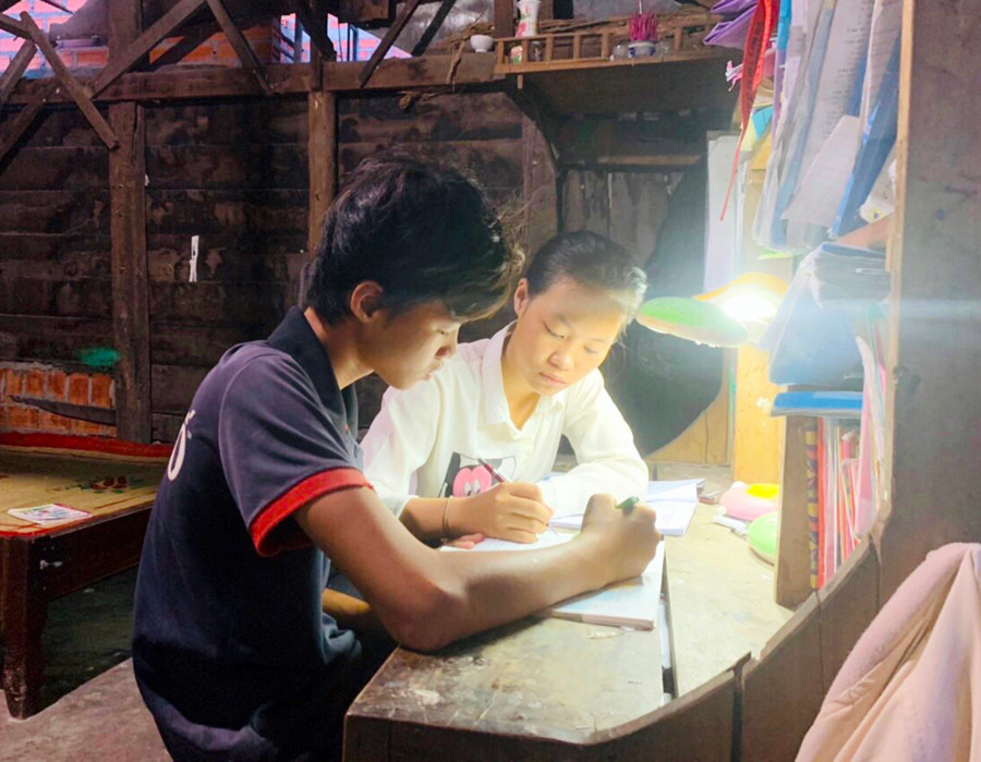 Em Phạm Thị Hồng Phương hướng dẫn em trai học bài. Ảnh: Thủy Bình 