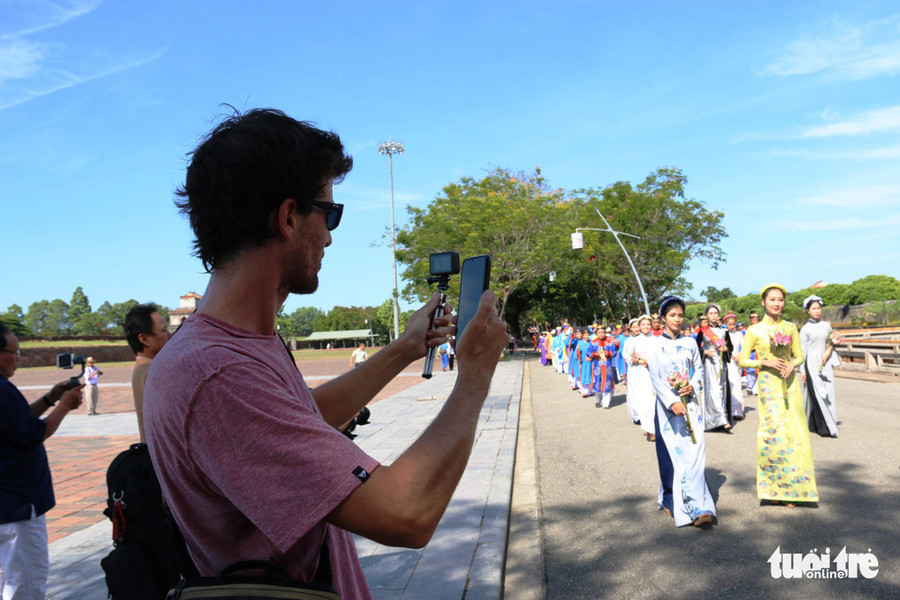  Một vị khách du lịch nước ngoài thích thú chụp ảnh đoàn diễu hành - Ảnh: NHẬT LINH