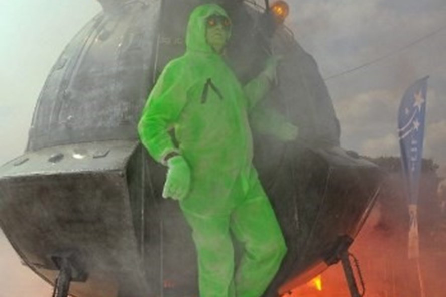 Một người cải trang thành người ngoài hành tinh bên cạnh mô hình giả đĩa bay tại sân bay UFO ở làng Ares, phía tây nam nước Pháp năm 2010. Ảnh: AFP