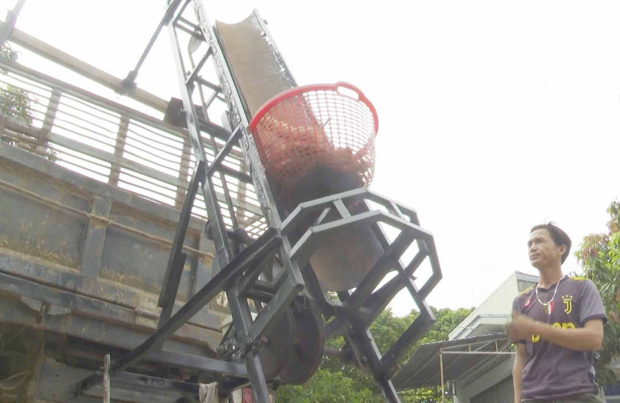 Anh Bùi Văn Hướng với chiếc băng tải do anh sáng chế, giúp nông dân đỡ vất vả mỗi khi vào vụ thu hoạch mì. Ảnh: MINH TRIỀU 