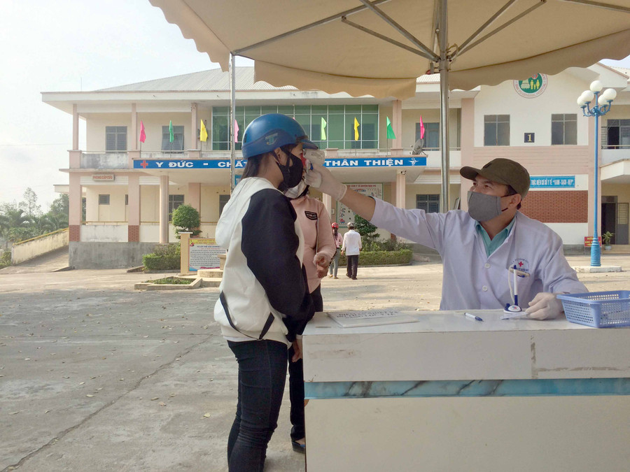 Bệnh nhân rửa tay sát khuẩn và đo thân nhiệt trước khi vào bệnh viện. Ảnh: Nguyễn Hiền 