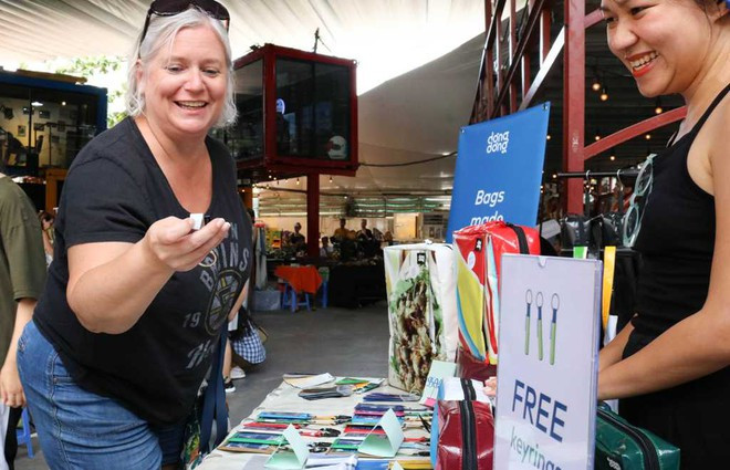 Khách nước ngoài thích thú với những sản phẩm tái chế từ bạt nhựa của nhóm. Ảnh:NGỌC THẢO