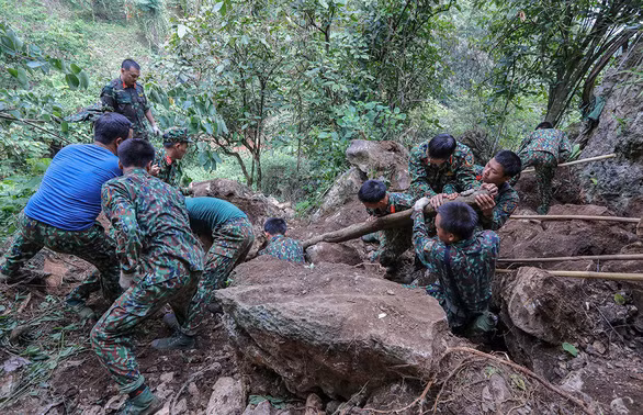 Chiến sĩ đang vần tảng đá trên bình độ 400 để phát lộ các di vật liệt sĩ - Ảnh: V.DŨNG