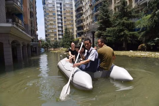  Người dân TP Vũ Hán-Trung Quốc di chuyển trên đường phố ngập lụt. Ảnh: Tân Hoa Xã