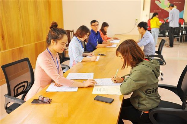  Các cán bộ phụ nữ Ủy ban huyện Hoa Lư, Ninh Bình, bộ phận một cửa mặc áo dài tiếp dân. (Ảnh: Minh Đức/TTXVN)