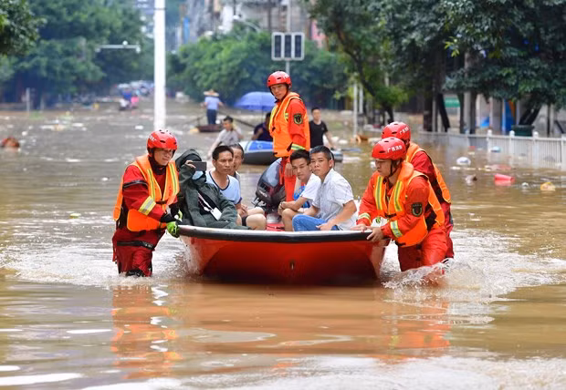  Lực lượng cứu hộ sơ tán người dân khỏi vùng ngập lụt. (Ảnh: THX/ TTXVN)