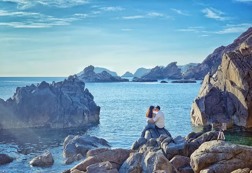 Các cặp đôi tranh thủ ghi lại khoảng khắc đẹp trước bình minh Eo Gió bằng chế độ chụp tự động của điện thoại. (Ảnh: Xuân Mai/Vietnam+)