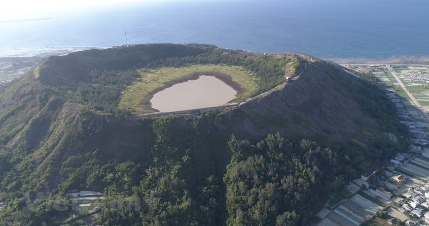 Từ trên cao nhìn xuống, miệng núi lửa Giếng Tiền hệt như 'chiếc chảo khổng lồ' nhô lên giữa biển trời huyện đảo Lý Sơn. Miệng núi lửa này rộng hàng trăm mét, cao 30-40 mét nghiêng về phía bắc, có niên đại khoảng 1 triệu năm. Ảnh: Tùng Lâm/Vietnam+ Từ trên cao nhìn xuống, miệng núi lửa Giếng Tiền hệt như 'chiếc chảo khổng lồ' nhô lên giữa biển trời huyện đảo Lý Sơn. Miệng núi lửa này rộng hàng trăm mét, cao 30-40 mét nghiêng về phía bắc, có niên đại khoảng 1 triệu năm. Ảnh: Tùng Lâm/Vietnam+