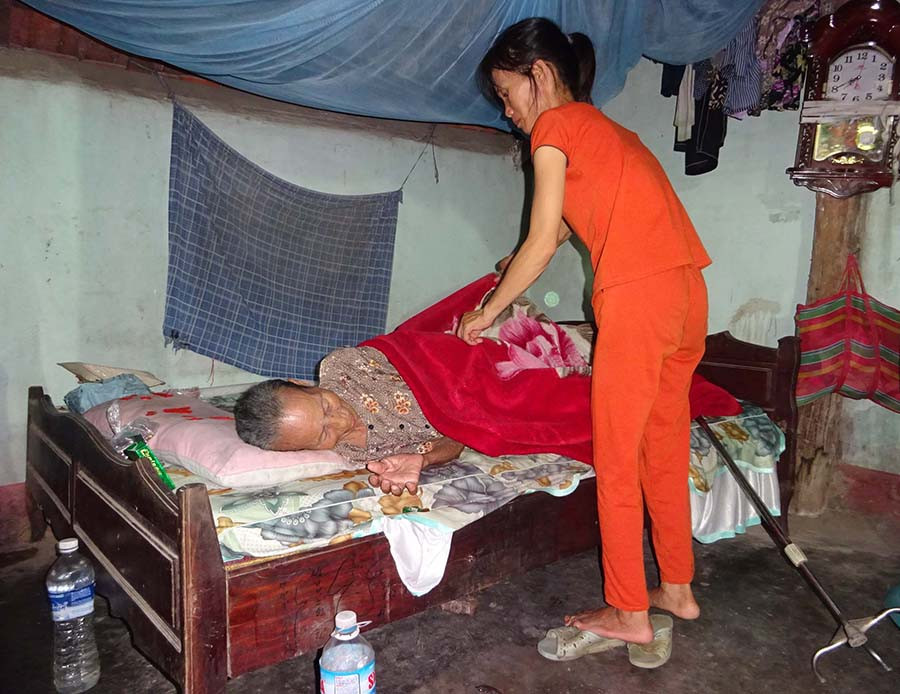  Chị Mai Thị Liêm chăm sóc mẹ già. Ảnh: H.P