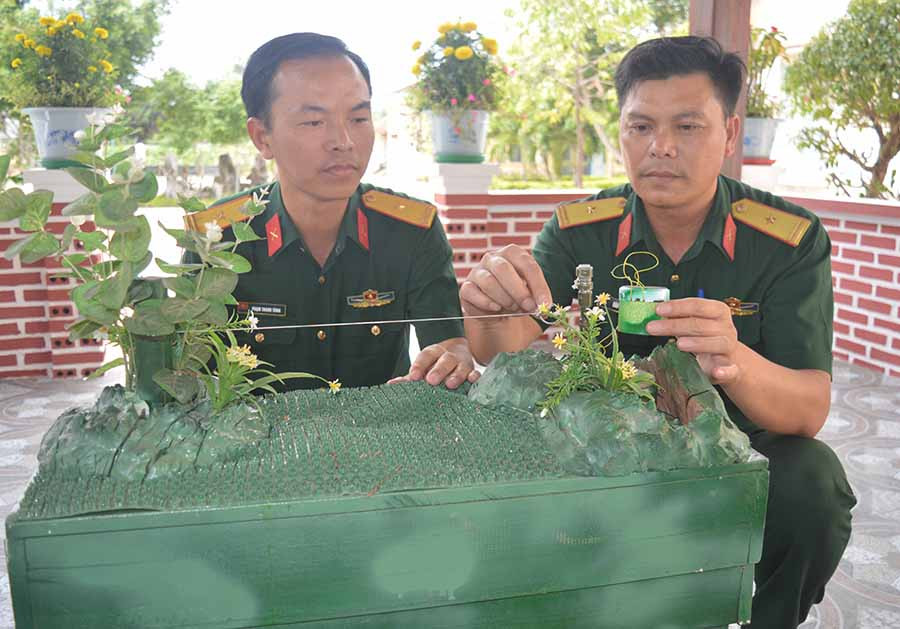  Thiếu tá Đào Xuân Tuyến (bìa phải) bên thiết bị kiểm tra thực hành dò, gỡ mìn vướng nổ. Ảnh: A.H