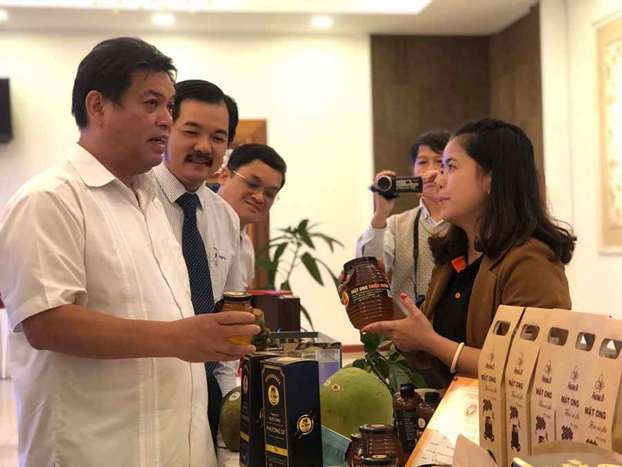  Phó Chủ tịch UBND tỉnh Kpă Thuyên (bìa trái) tham quan gian hàng trưng bày của HTX Mật ong Phương Di Ia Grai tại một hội nghị xúc tiến thương mại. Ảnh: S.C