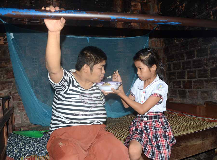  Hết giờ học, bé Trúc phụ giúp ông bà chăm mẹ bị bệnh liệt giường. Ảnh: Đ.P