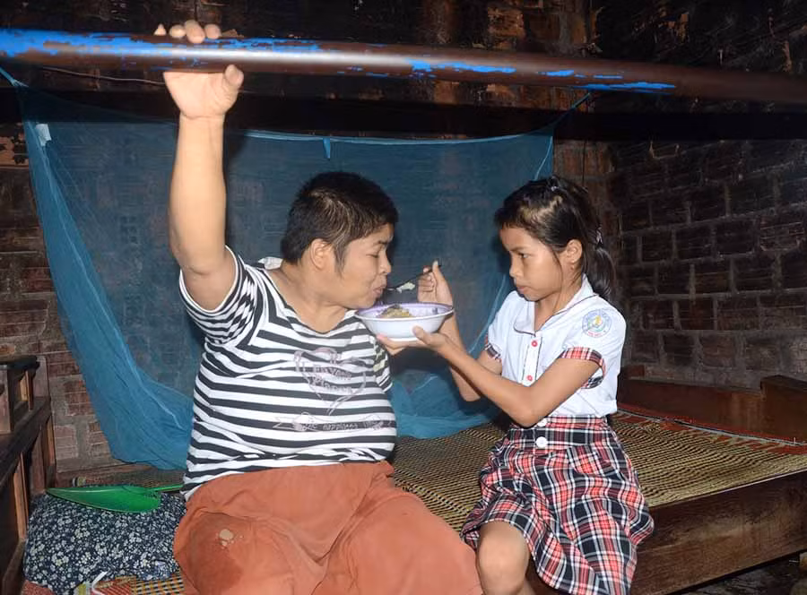  Hết giờ học, bé Trúc phụ giúp ông bà chăm mẹ bị bệnh liệt giường. Ảnh: Đ.P