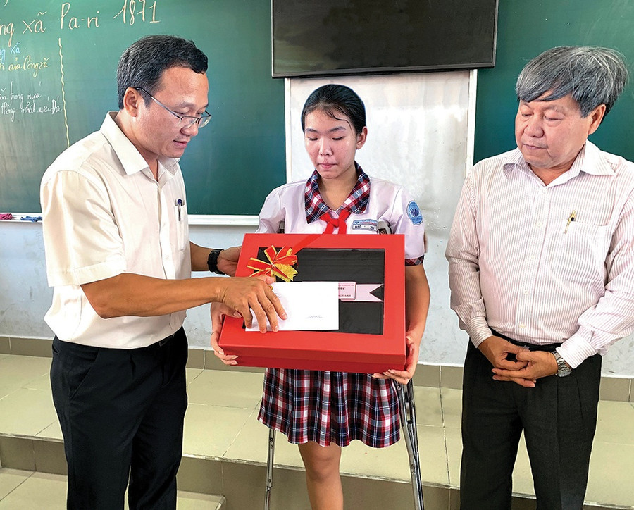 Phó chủ tịch chuyên trách Ủy ban ATGT Quốc gia Khuất Việt Hùng trao tận tay quà và thư của Thủ tướng cho bé Hoàng Oanh. Ảnh: Đỗ Loan