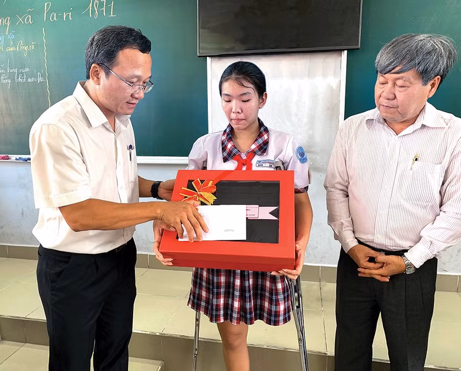 Phó chủ tịch chuyên trách Ủy ban ATGT Quốc gia Khuất Việt Hùng trao tận tay quà và thư của Thủ tướng cho bé Hoàng Oanh. Ảnh: Đỗ Loan