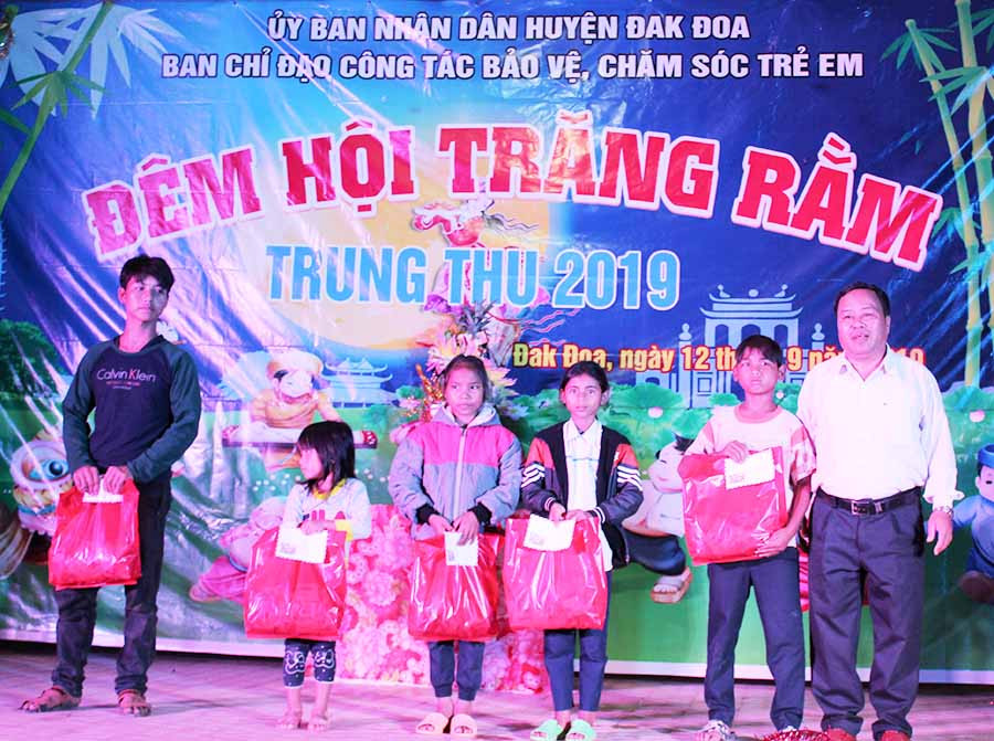  Đồng chí Hoàng Nhưn-Phó Chủ tịch UBND huyện Đak Đoa (bìa phải) trao quà cho trẻ nghèo vượt khó học giỏi. Ảnh: Lương Thế
