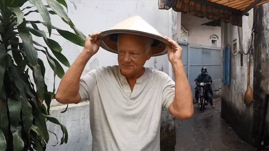  Ông Ken Reesing đội nón lá và phụ bán cháo với bà Lan