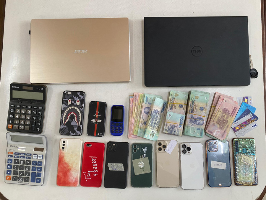 Tiền mặt, điện thoại, laptop tang vật tạm giữ. Ảnh: Nguyễn Tú