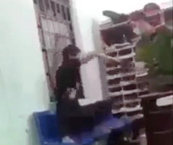 Cán bộ công an phường dí roi điện vào người nam thanh niên. Ảnh: Cắt từ clip