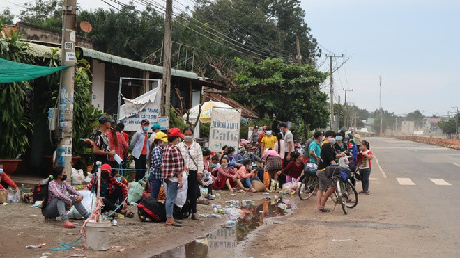 Người dân ngồi chờ xe đến đón, chở về Đắk Nông. Ảnh: Hoàng Giáp 