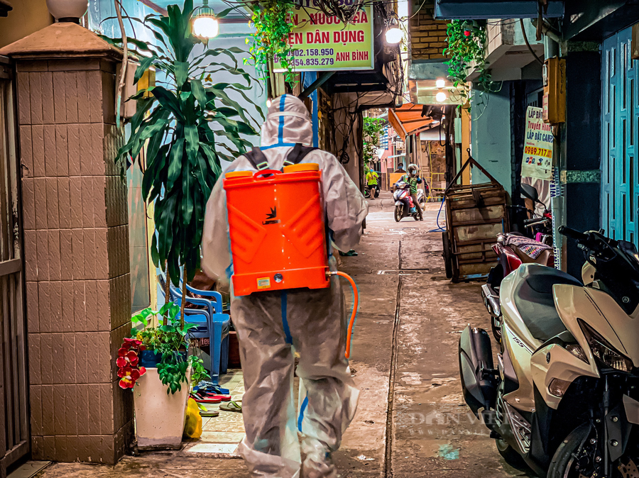 Trước khi đến nhà nạn nhân mất do Covid-19, để tiếp nhận mang đi mai táng một thành viên trong đội sẽ vào trước để phun khử khuẩn. Ảnh: Chinh Hoàng