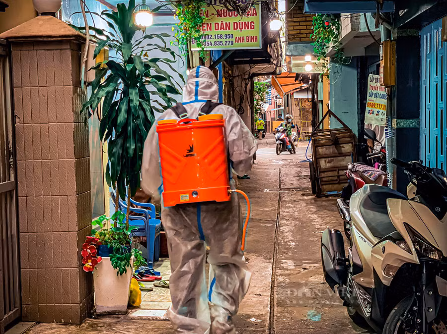 Trước khi đến nhà nạn nhân mất do Covid-19, để tiếp nhận mang đi mai táng một thành viên trong đội sẽ vào trước để phun khử khuẩn. Ảnh: Chinh Hoàng