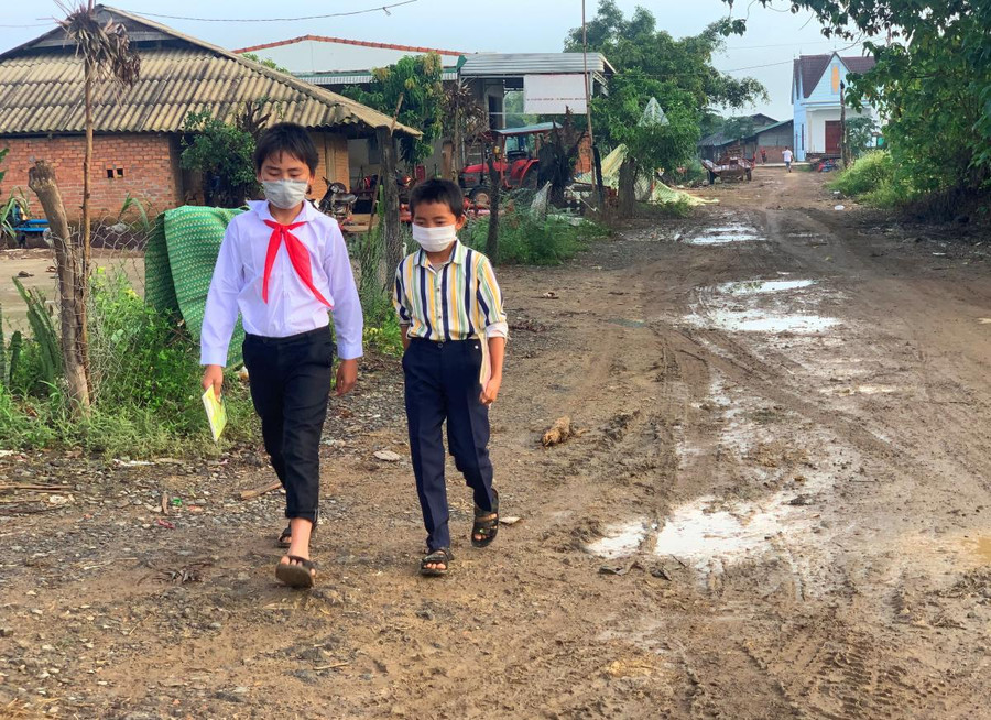 Em Vừ A Phong cùng bạn cắp sách đi bộ trên con đường lầy lội tại làng Mông (xã Nam Ka, huyện Lắk) để đến trường học.