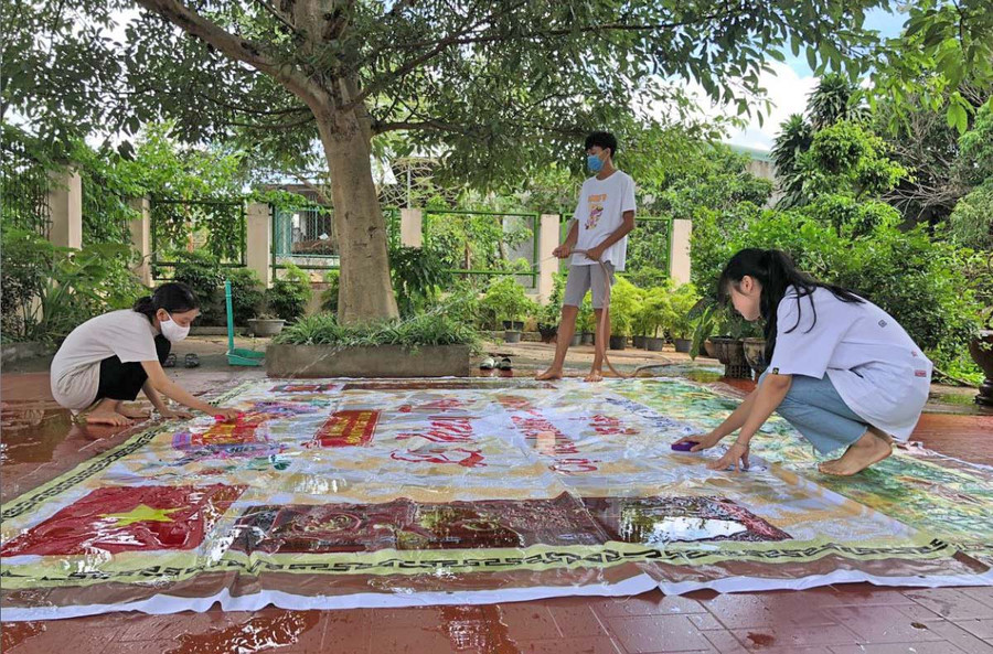 Các thành viên nhóm sáng tạo của Trường THPT Nguyễn Bỉnh Khiêm (huyện Chư Sê) làm sạch bạt hiflex sau khi thu gom để tái chế thành túi đựng đồ. Ảnh: Thủy Bình