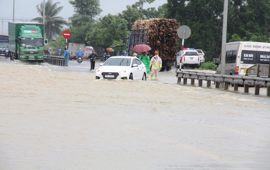 Nước tràn qua tuyến QL1 địa bàn Quảng Nam gây ngập sâu khiến các phương tiện đi lại khó khăn. Ảnh: Mạnh Cường 