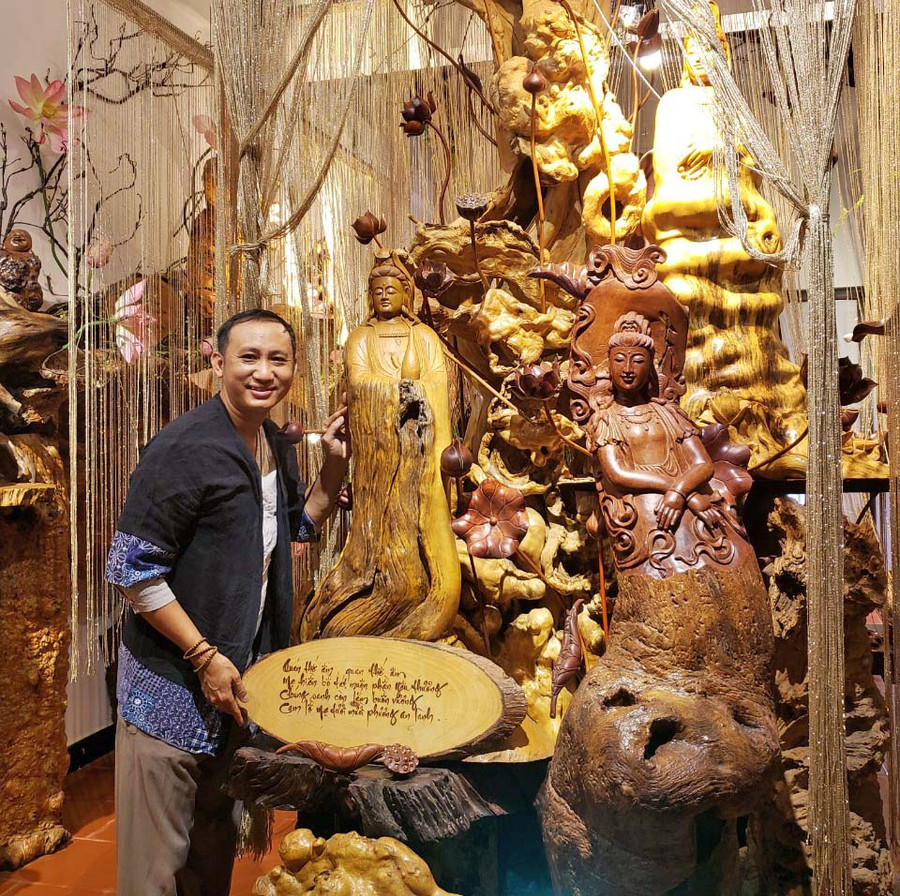 Anh Trần Đức Vinh bên những tác phẩm làm từ gỗ lũa. Ảnh: Nguyễn Tú