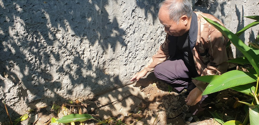 Nhà thơ Trần Nhuận Minh và bài thơ của Nguyễn Cẩn bị vùi sâu dưới lòng đất. Ảnh: Nguyễn Hùng