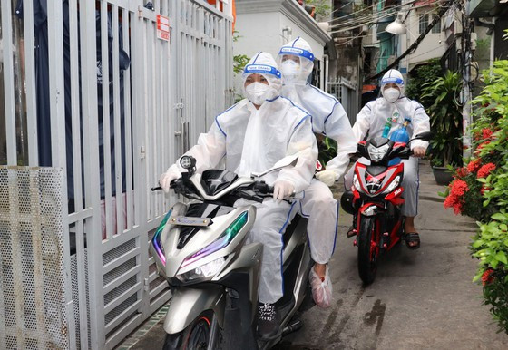 Các “hoa tiêu” tại phường 1 (quận 4) chở bác sĩ quân y đến thăm khám F0 tại hẻm nhỏ. Ảnh: Thái Phương