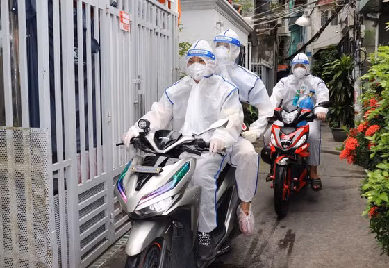 Các “hoa tiêu” tại phường 1 (quận 4) chở bác sĩ quân y đến thăm khám F0 tại hẻm nhỏ. Ảnh: Thái Phương