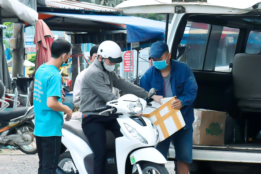 Nhân viên nhà xe đeo khẩu trang khi giao nhận hàng hóa tại bãi đỗ xe Trung tâm Thương mại Pleiku. Ảnh: Đức Thụy