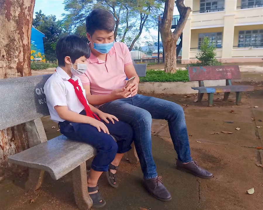 Thầy Trần Văn Nam-giáo viên Tổng phụ trách Đội, Trường Tiểu học và THCS Lê Văn Tám (xã Trà Đa, TP. Pleiku) hướng dẫn học sinh cách sử dụng điện thoại để học tập. Ảnh: Mộc Trà