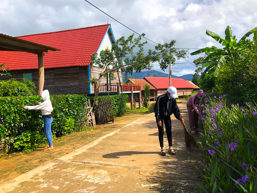 Hội viên phụ nữ làng Nhang Lớn chăm sóc con đường hoa. Ảnh: Ngọc Minh