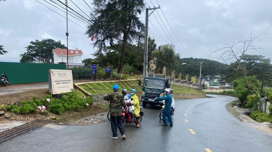 Lực lượng dân quân hướng dẫn xe cộ không đi vào làng hoa Vạn Thành nơi mới phát hiện ổ dịch Covid-19. Ảnh: Lâm Viên