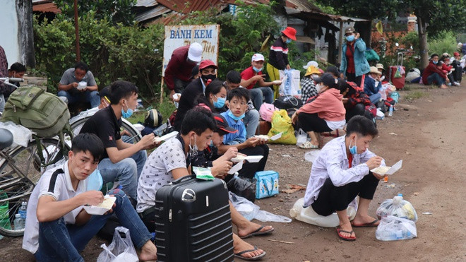 Bữa ăn vội được các nhà hảo tâm phát tặng khi đang chờ đợi phương tiện đưa về quê. Ảnh: Hoàng Giáp 