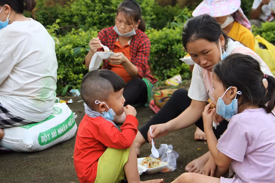 Chị Sùng Thị Tung chăm sóc cho 2 con nhỏ trong lúc chờ xe. Ảnh: Hoàng Bình